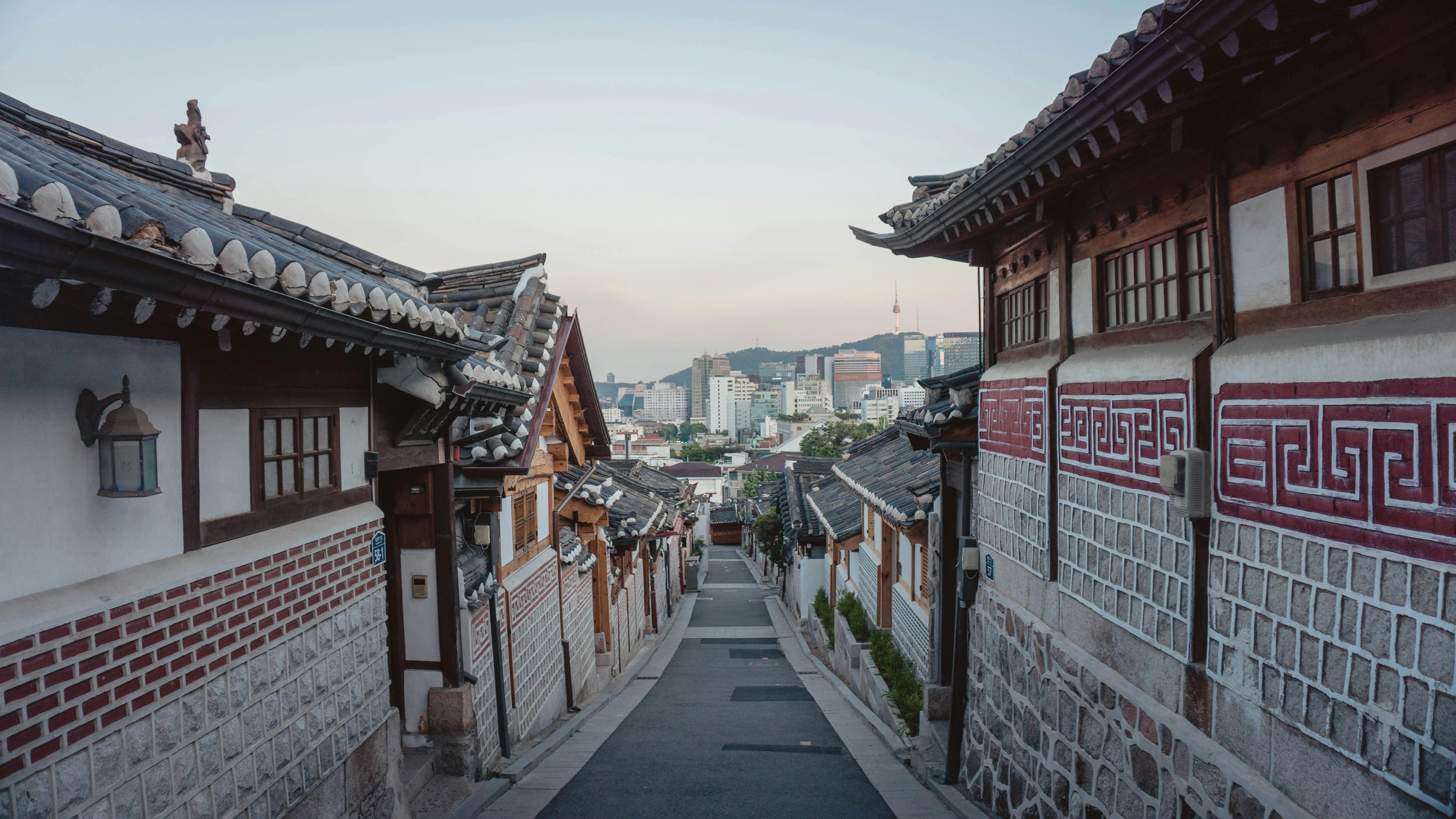 Traditional hanok houses lining a lane with the Seoul skyline beyond in South Korea