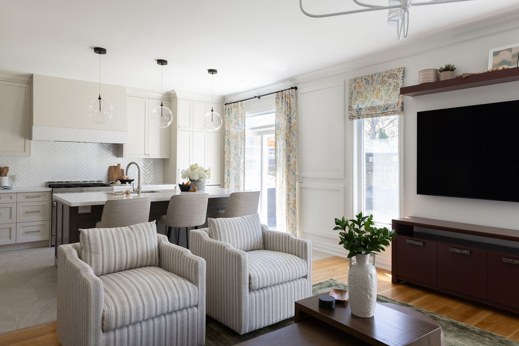 living room with striped armchairs, open concept butter kitchen, wine maroon sideboard custom ottoman