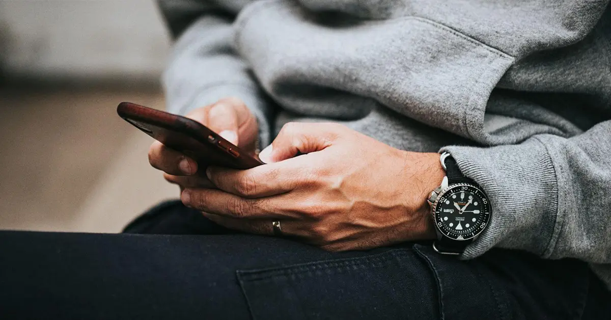 Close-up of a person holding a smartphone in their lap