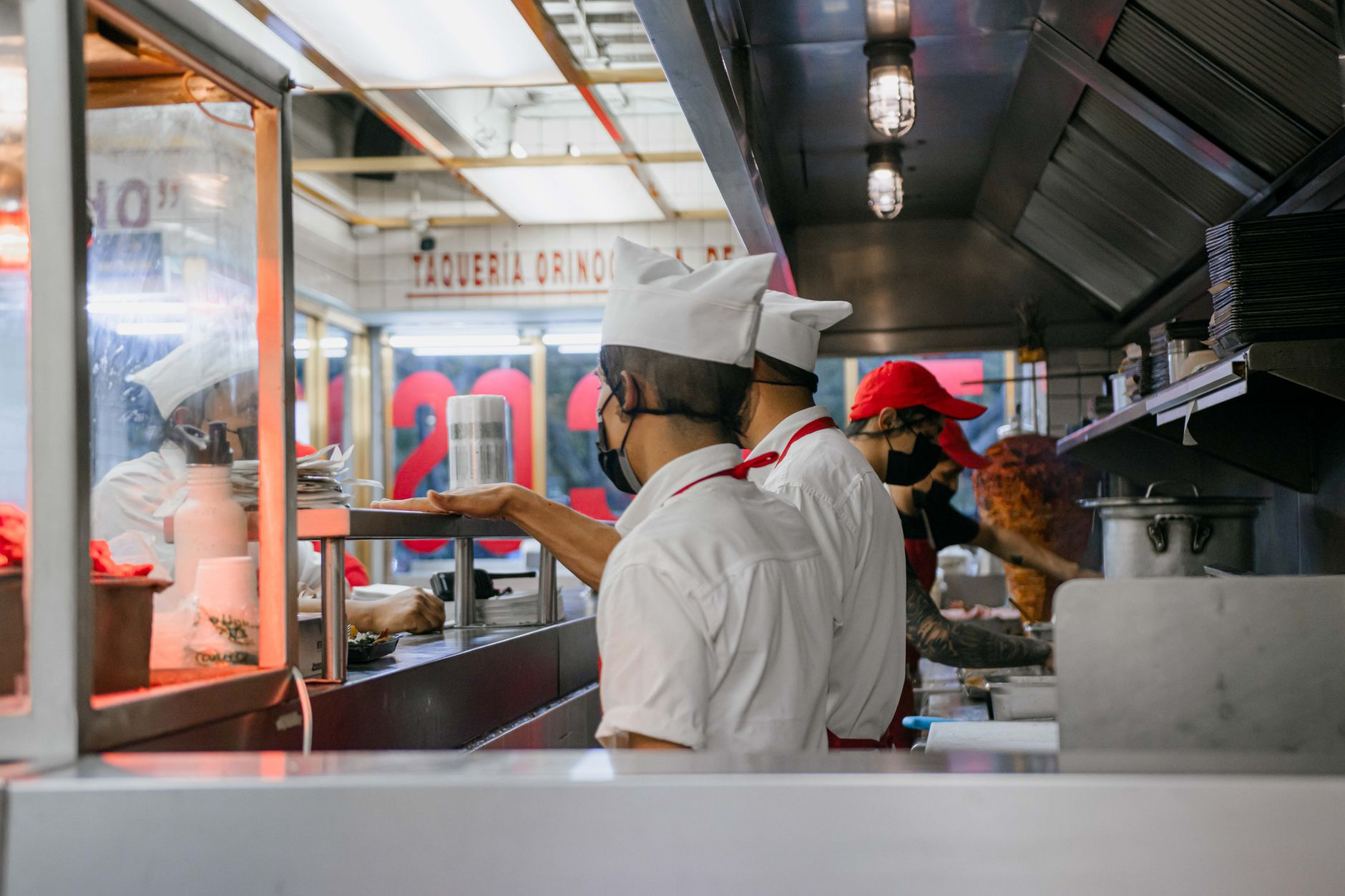 Culinary staff in uniform preparing meals in a bustling restaurant kitchen.