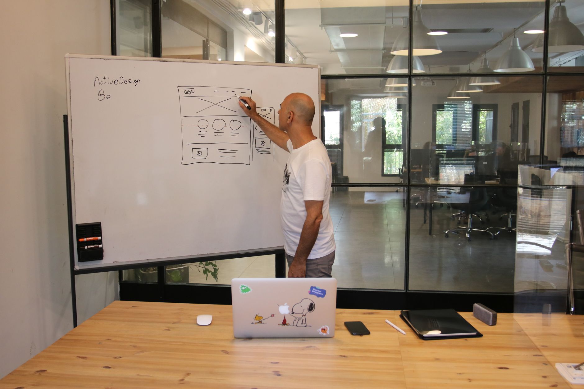 Employee drawing a strategy draft on a whiteboard in a contemporary office.