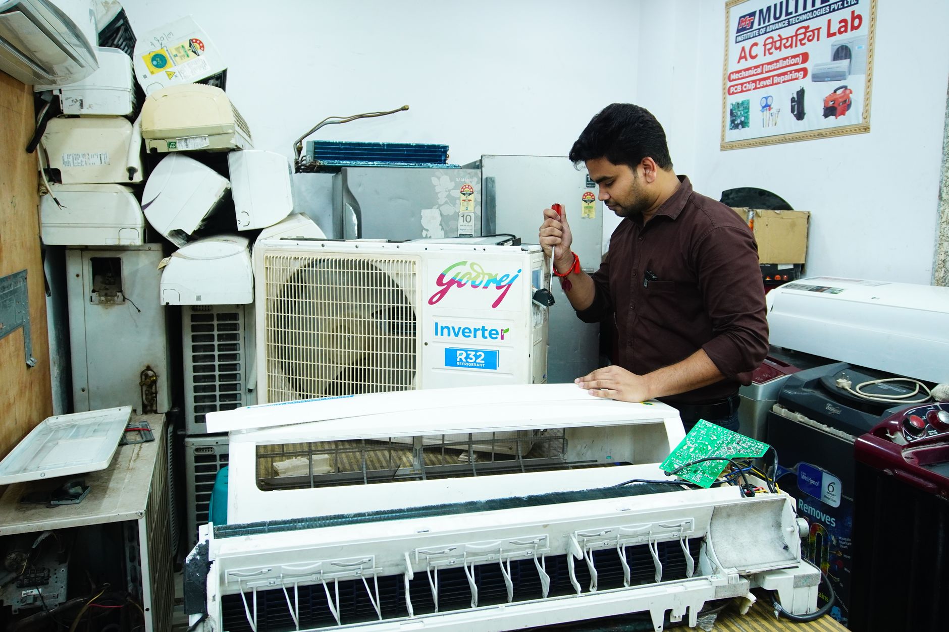 Technician repairing an air conditioner unit in a workshop.