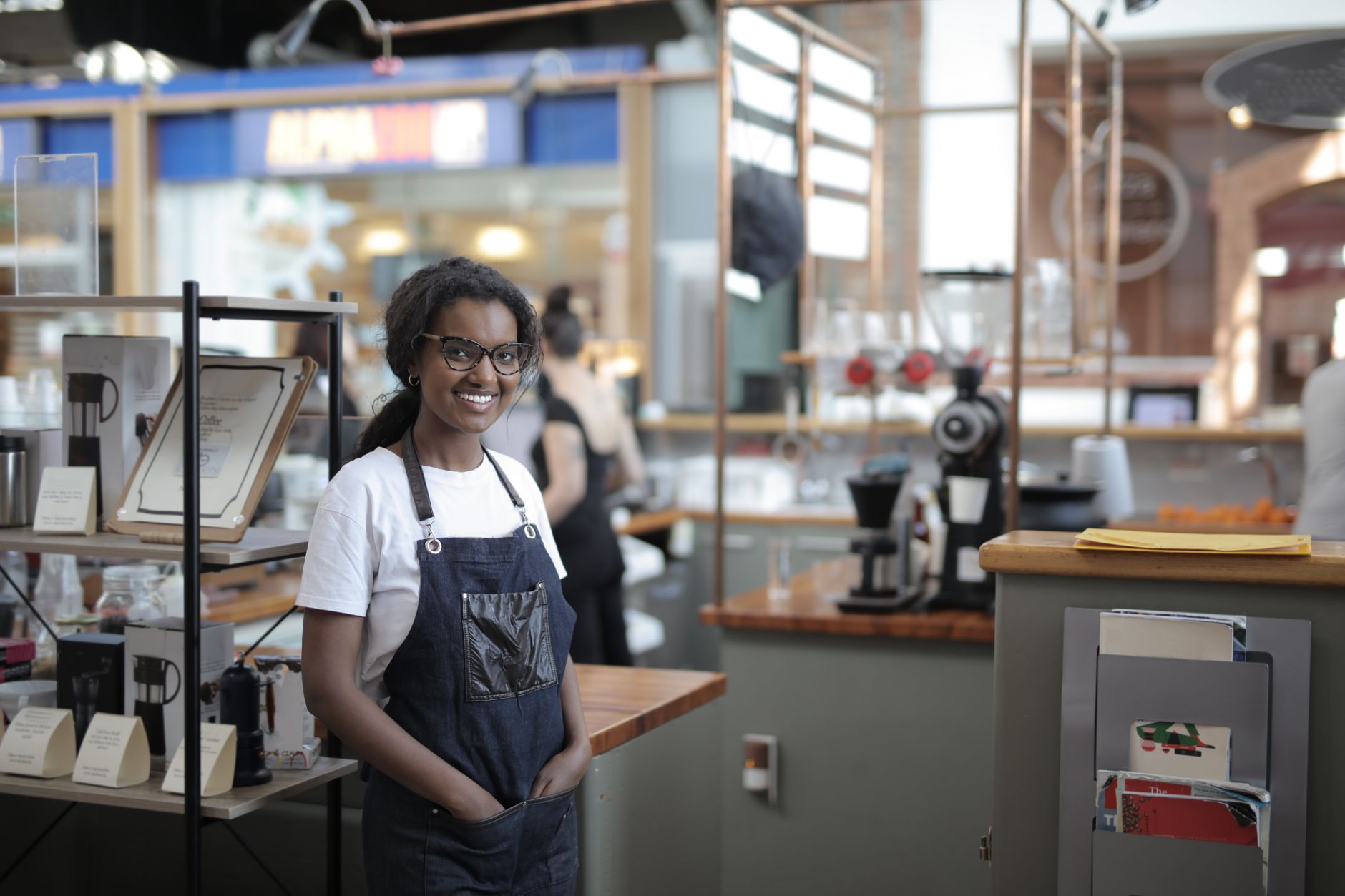 Smiling barista standing in a stylish cafe, showcasing entrepreneurial spirit.