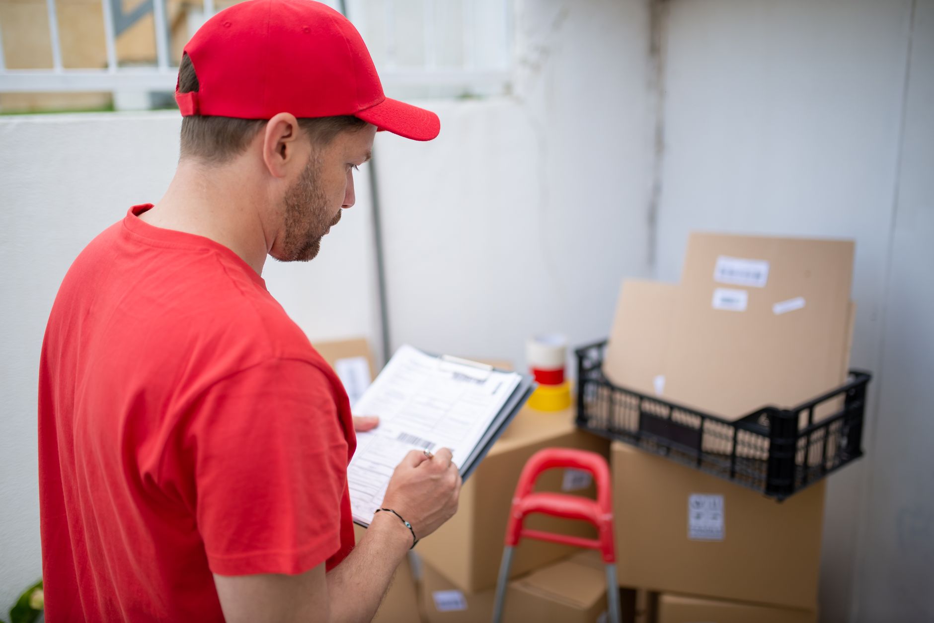 Delivery person in uniform checking packages outdoors.