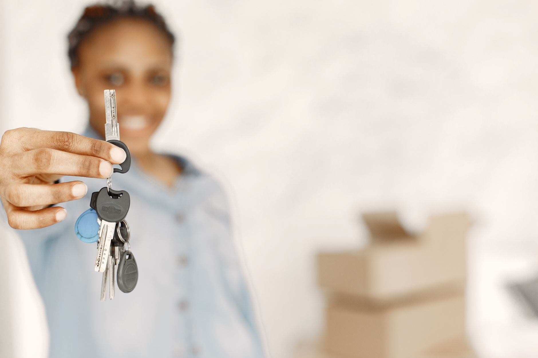 Close-up of a woman holding keys with a blurred background, symbolizing a new home.