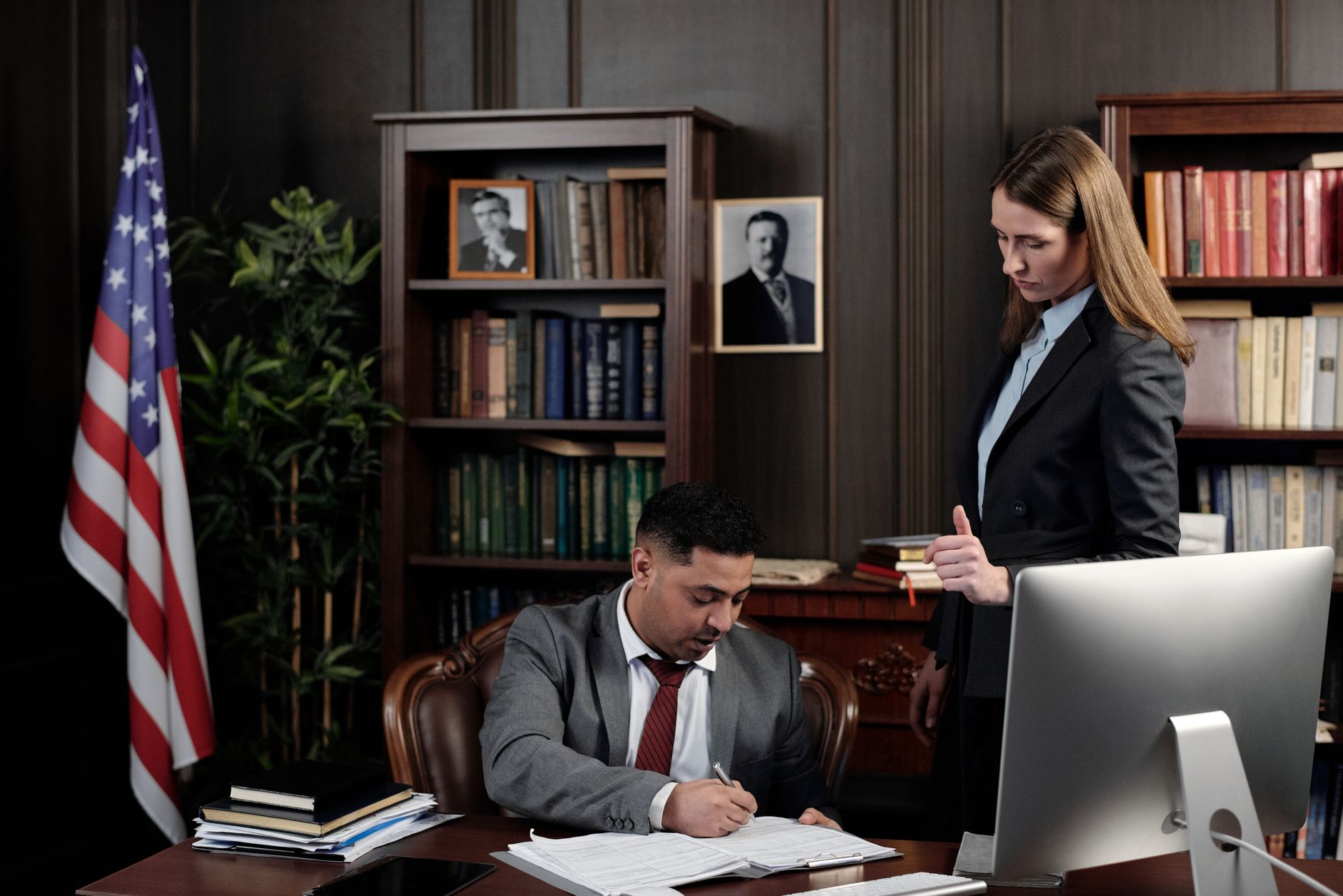 Legal professionals discussing documents at a desk in a law office.
