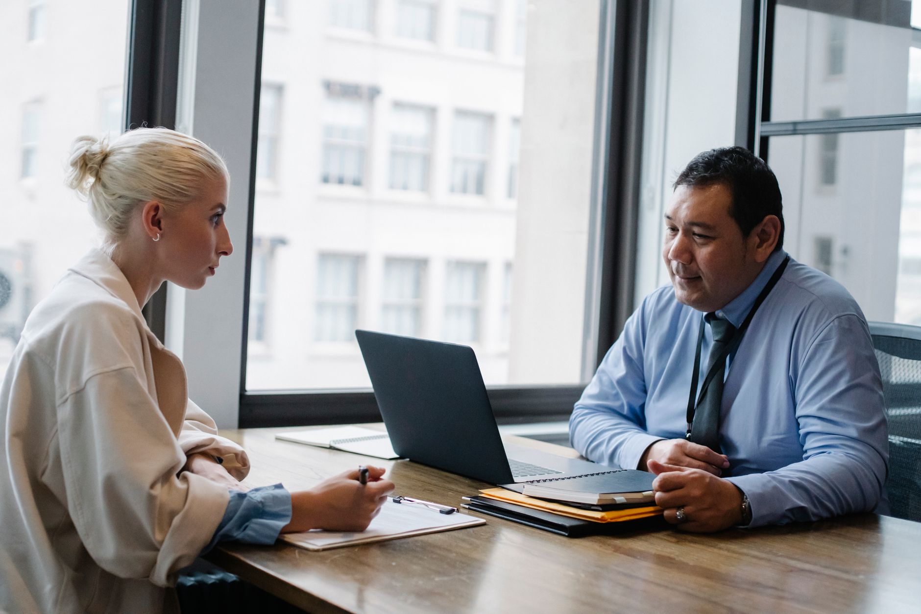 Hiring manager interviewing a candidate filling in an information form on a clipboard.