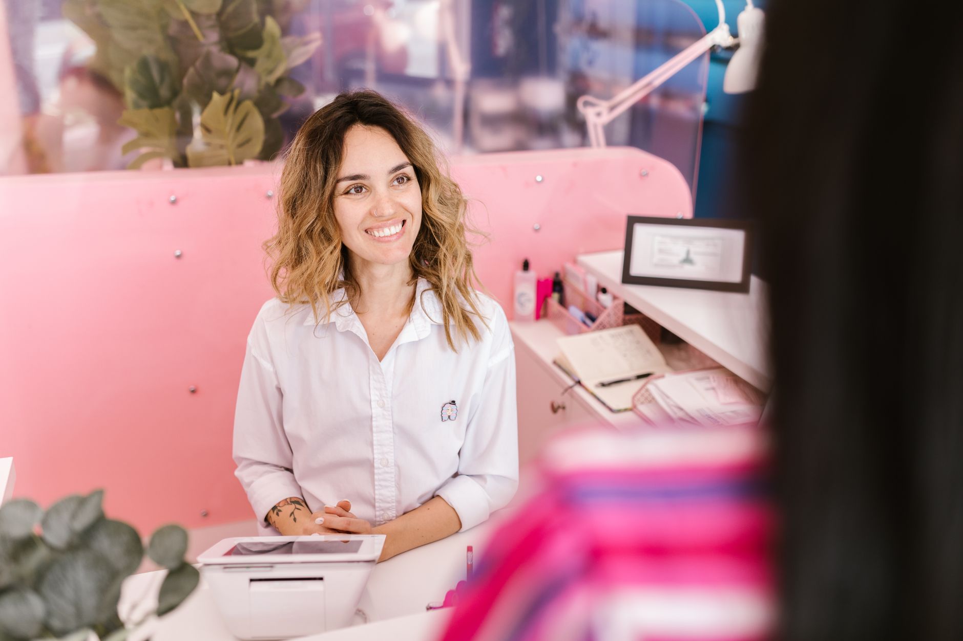 Smiling receptionist at a front desk, welcoming clients with a friendly demeanor.