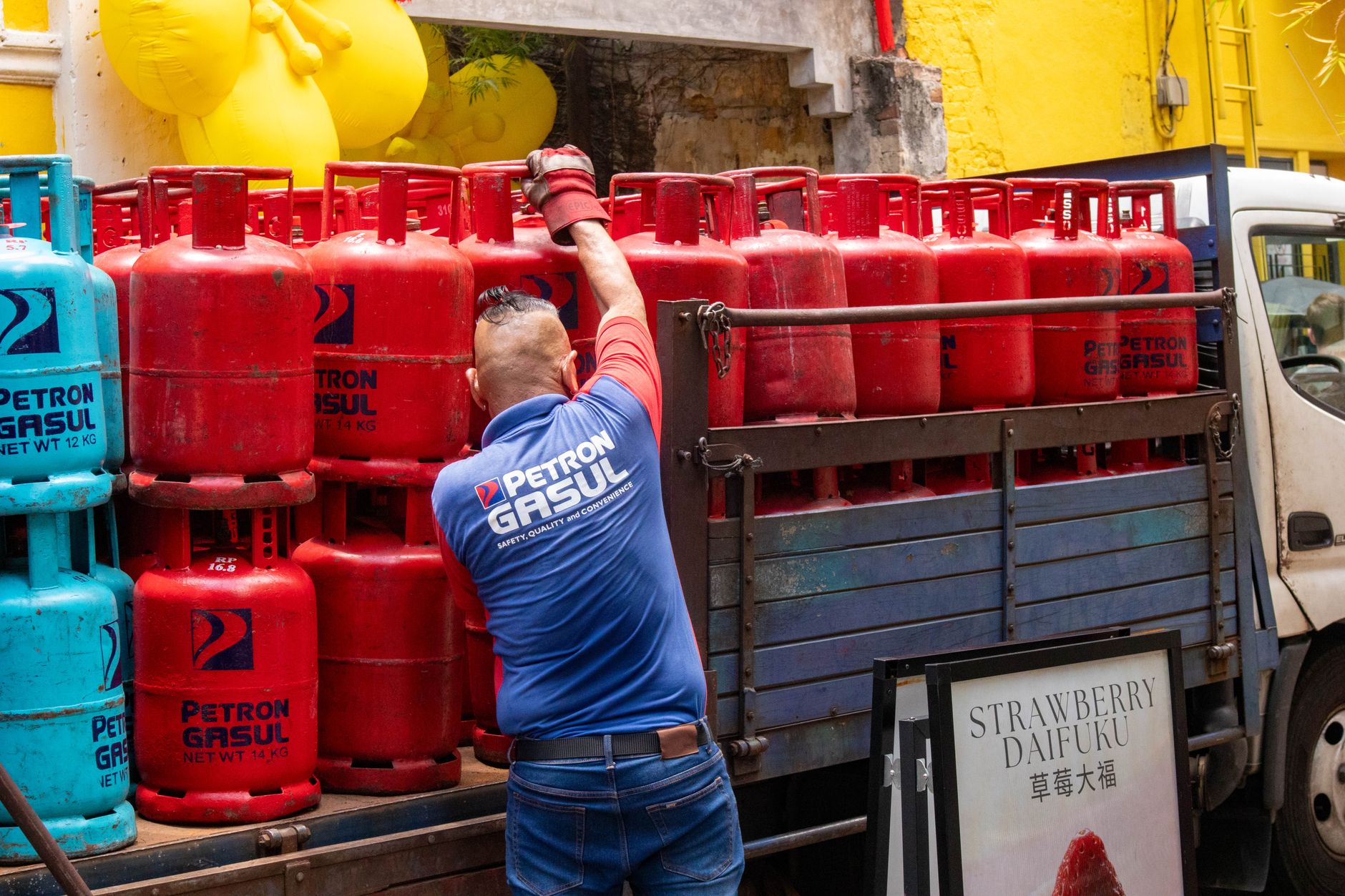 Delivery worker loading propane cylinders onto a truck