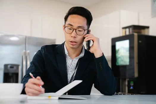 Man on a phone call confirming details and taking notes