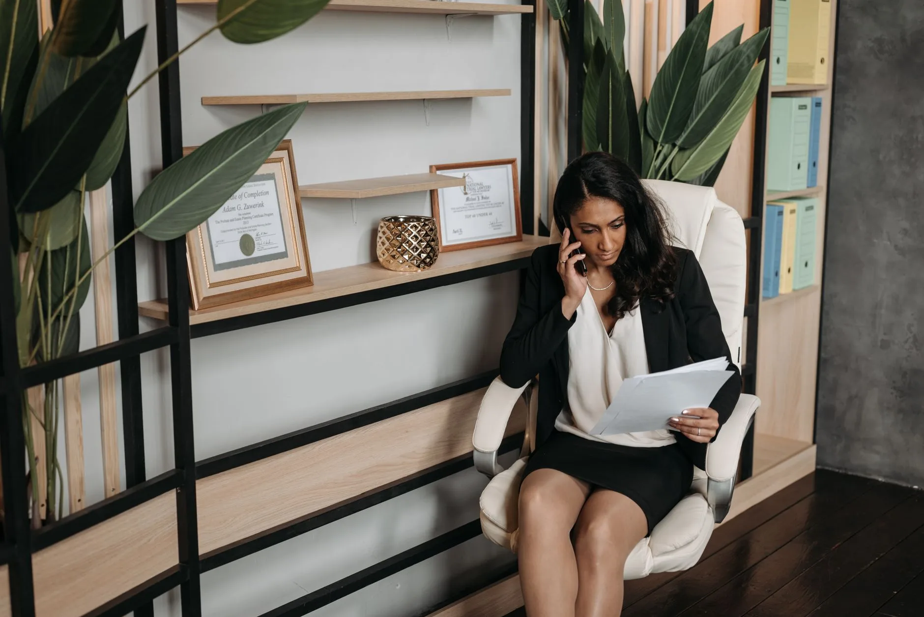 Office assistant reviewing documents during a phone call at her desk
