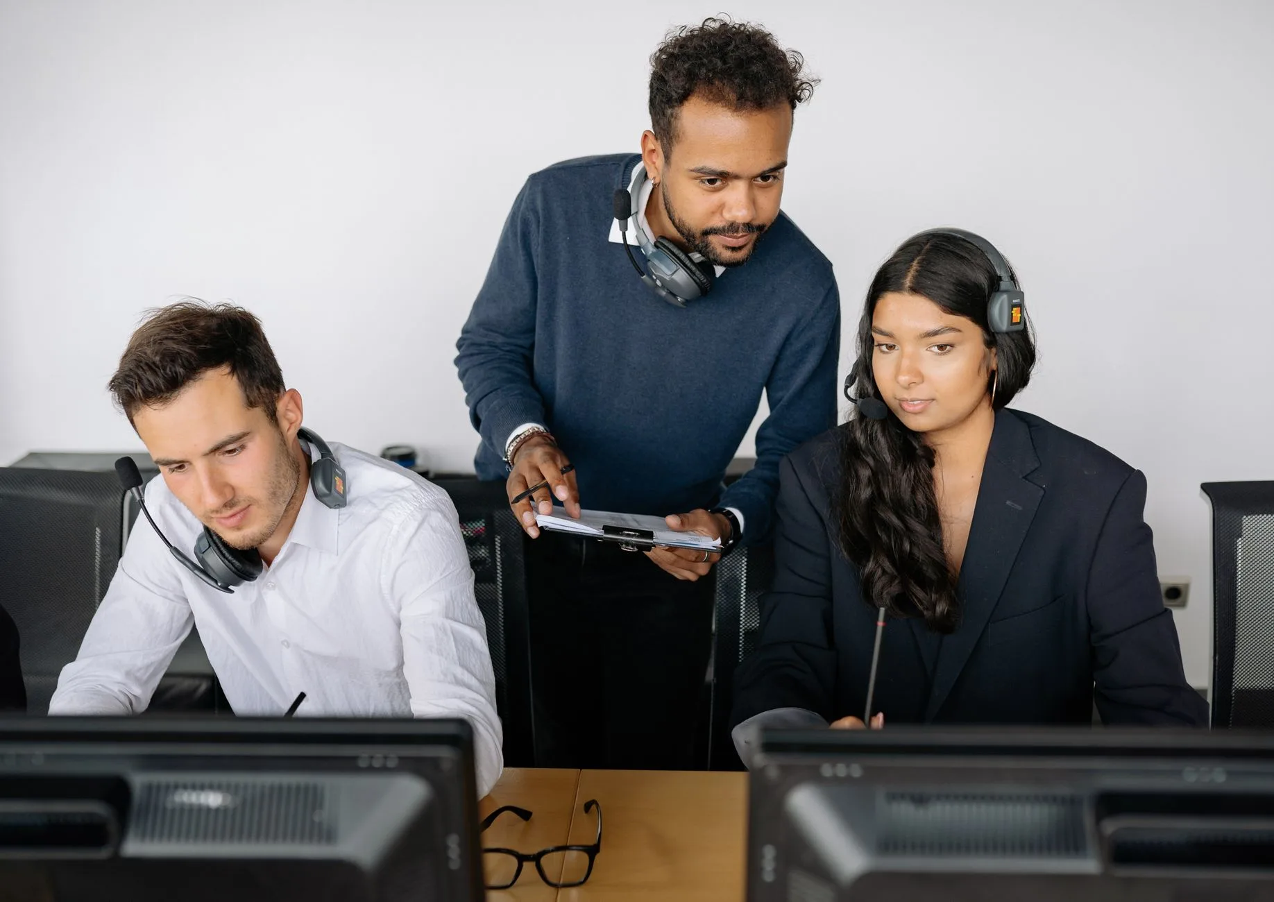 Supervisor reviewing a call with two agents at their desks