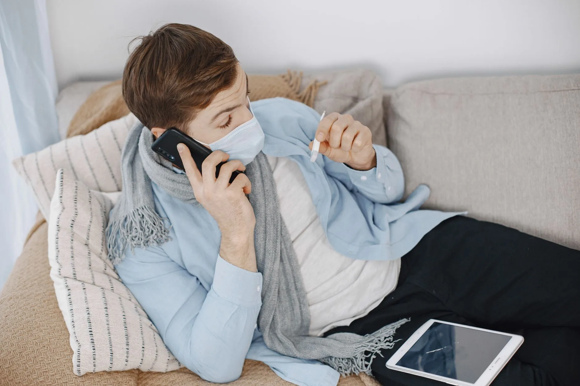 Patient calling a clinic from home while resting on the sofa