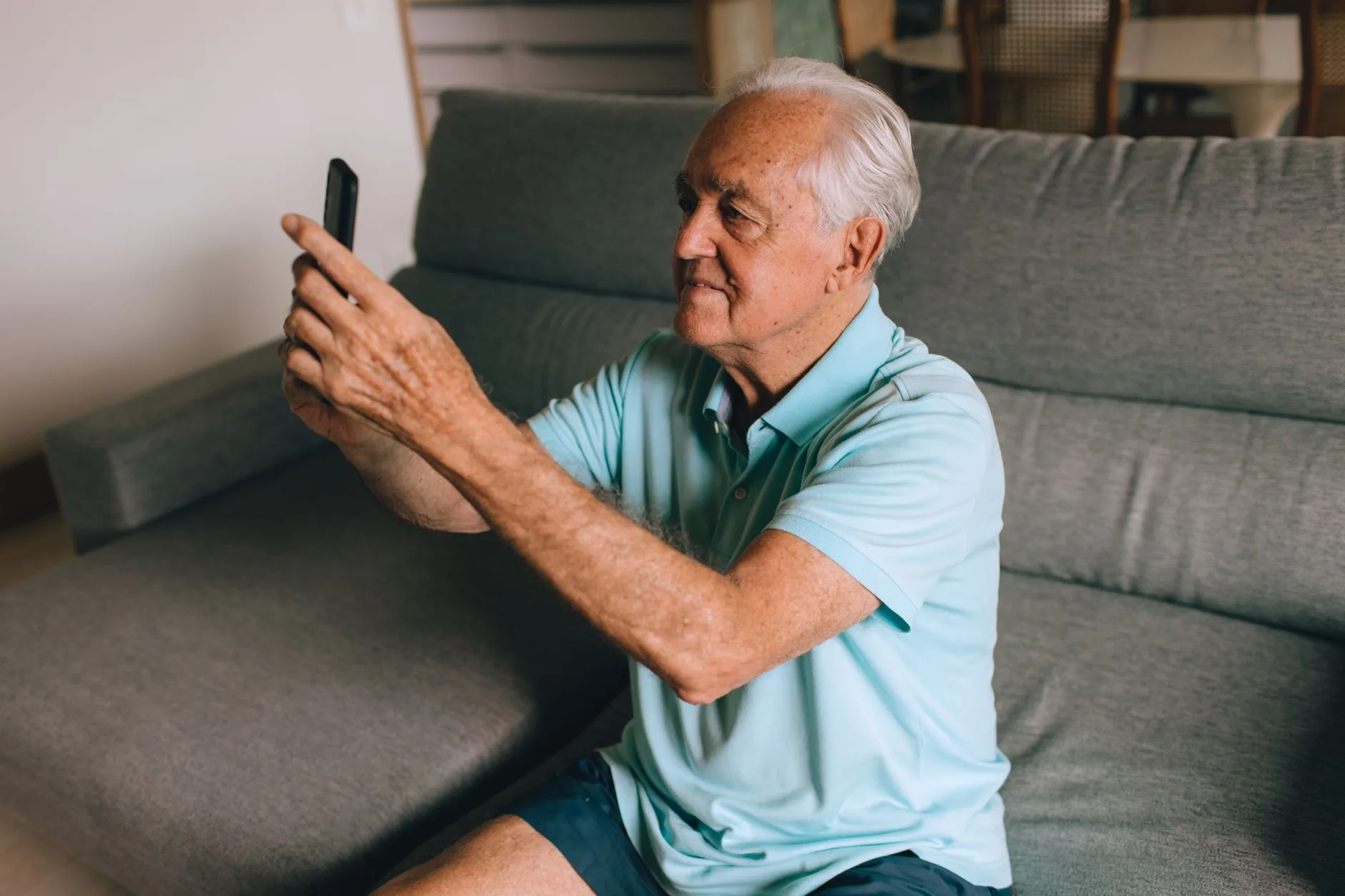 Senior man checking his smartphone at home