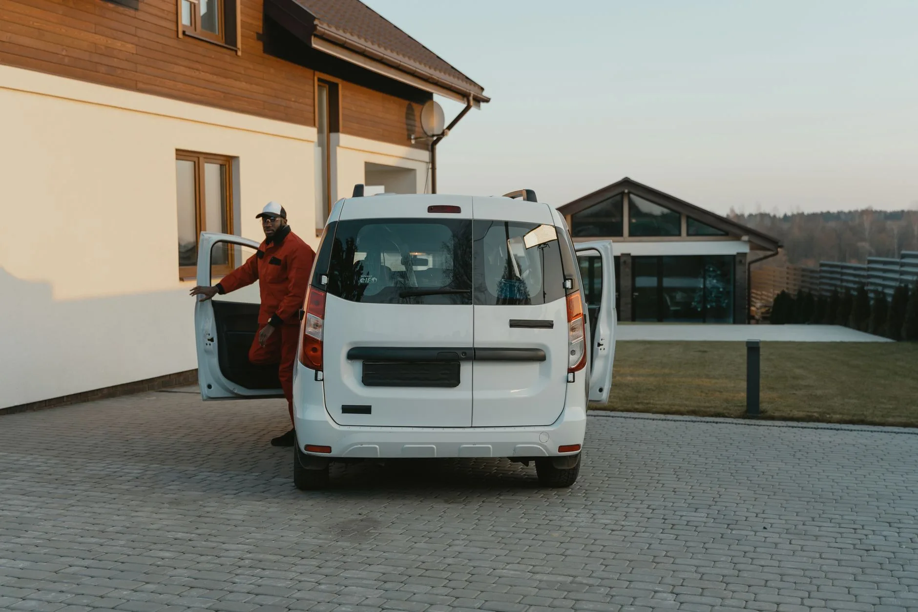 Service technician stepping out of a white van in a residential driveway