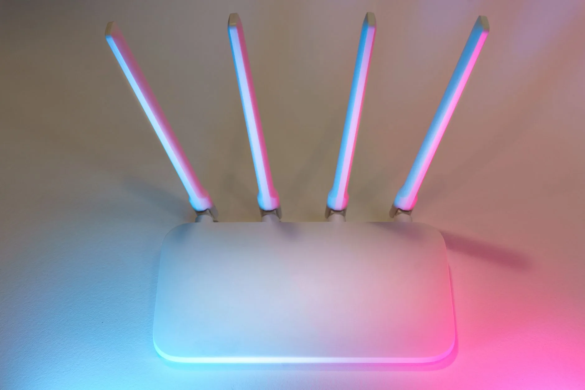 White Wi-Fi router with four antennas lit in pink and blue