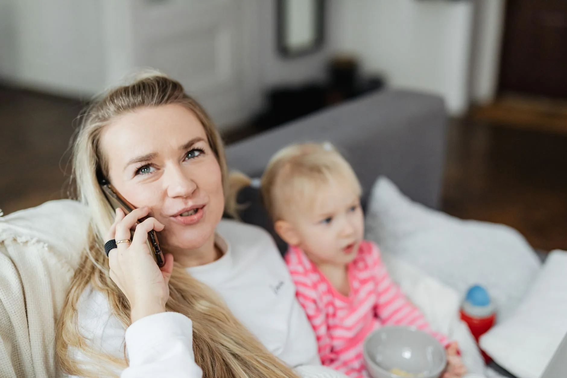 Woman holding a toddler while on a phone call at home