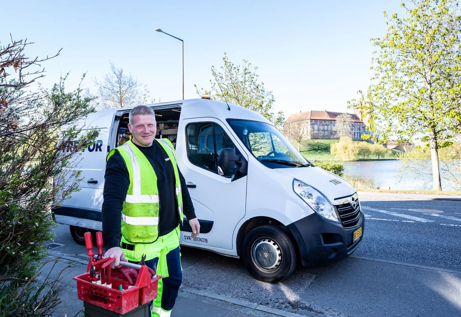 Technician in a high-visibility vest standing beside a white service van