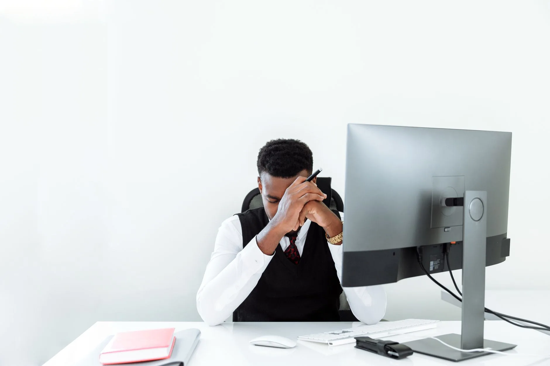 Office worker with his head in his hand in front of a desktop monitor