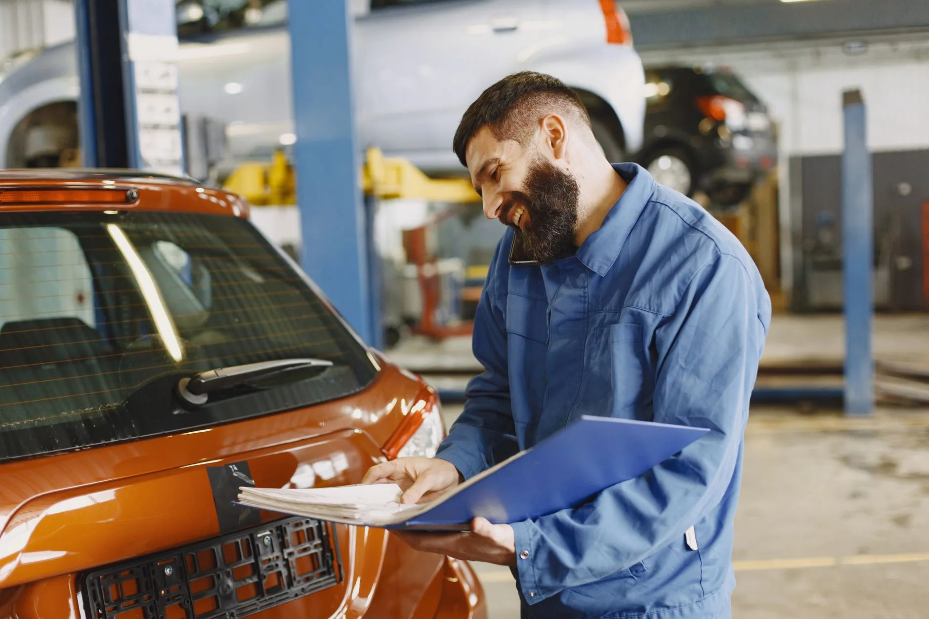 Mechanic inspecting a car with a clipboard in a repair shop