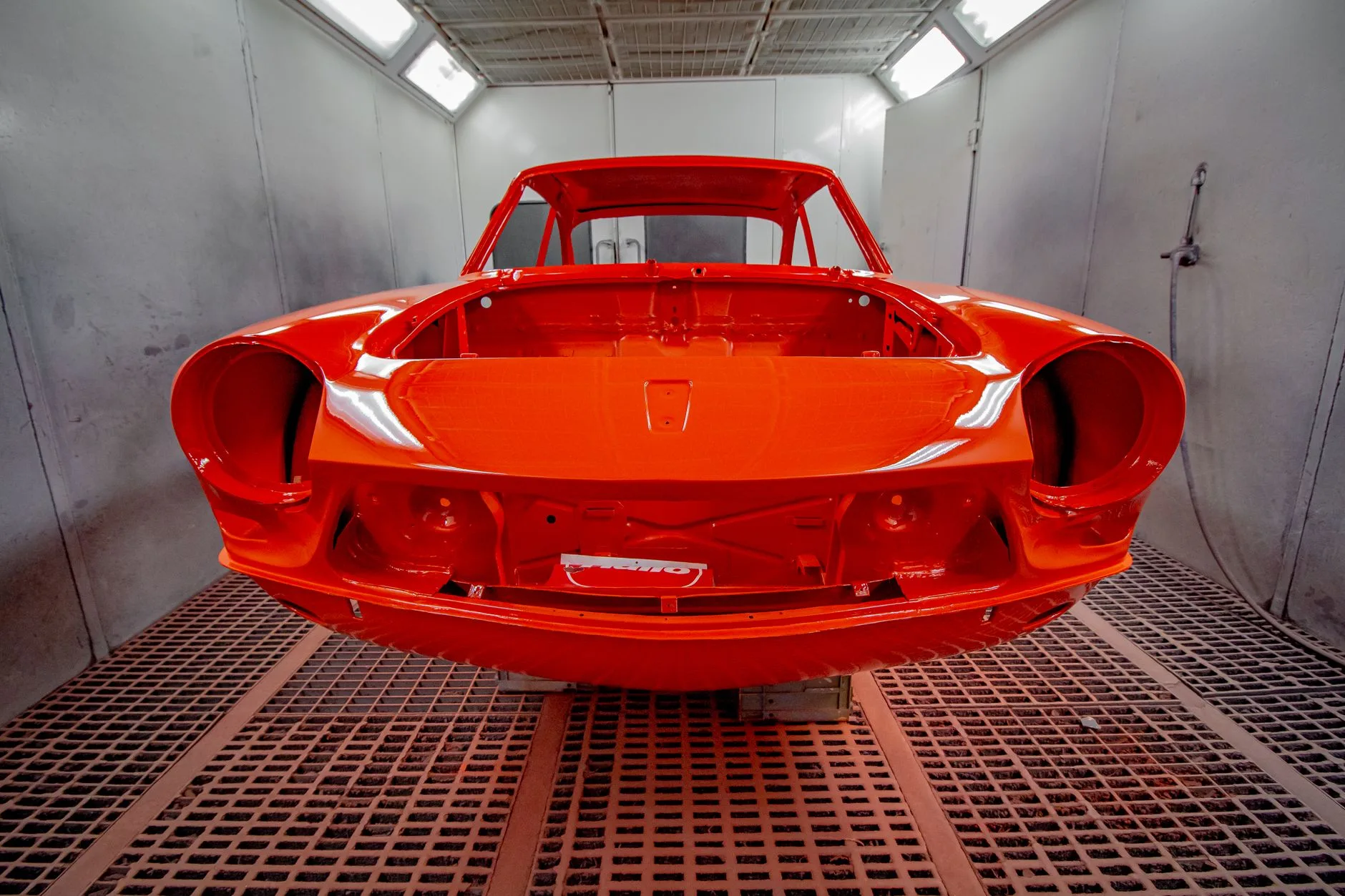 Car body freshly painted red in a spray booth