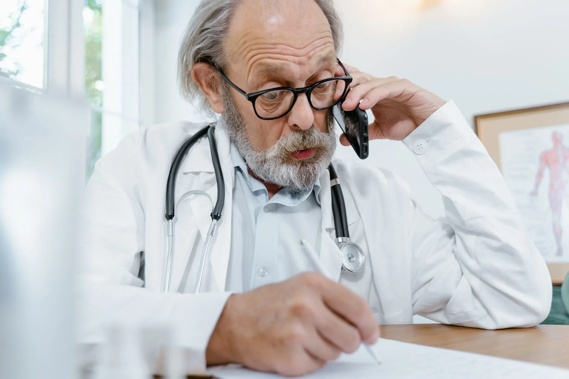 Physician taking a transferred call at his desk