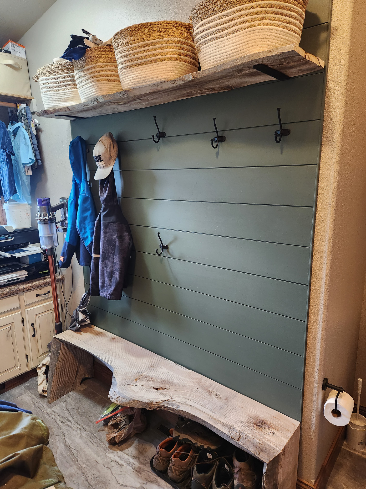 Entryway coat hanging area with wooden bench built by Potterbilt Homes.