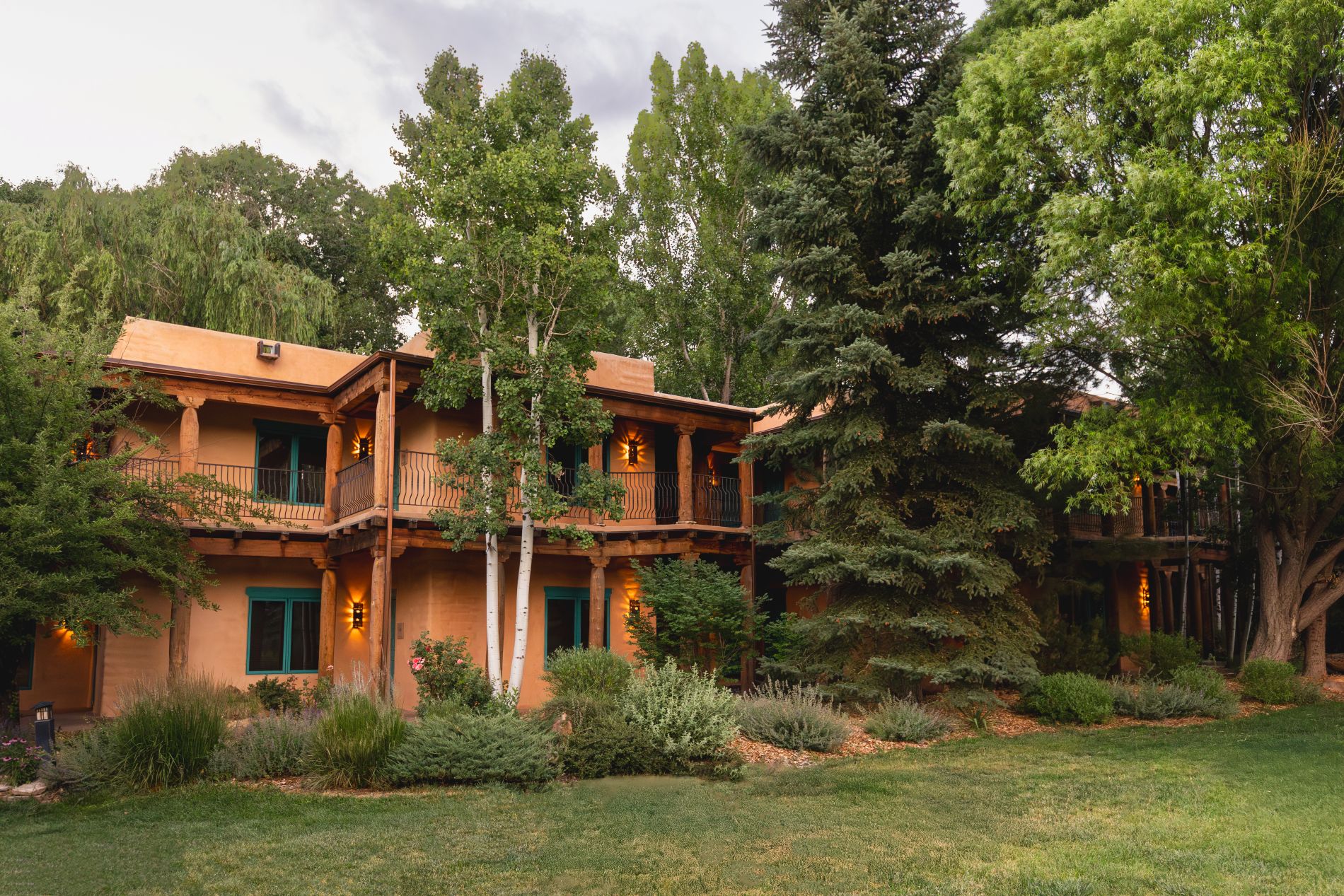 Grounds with trees and adobe 2 story building with guest rooms