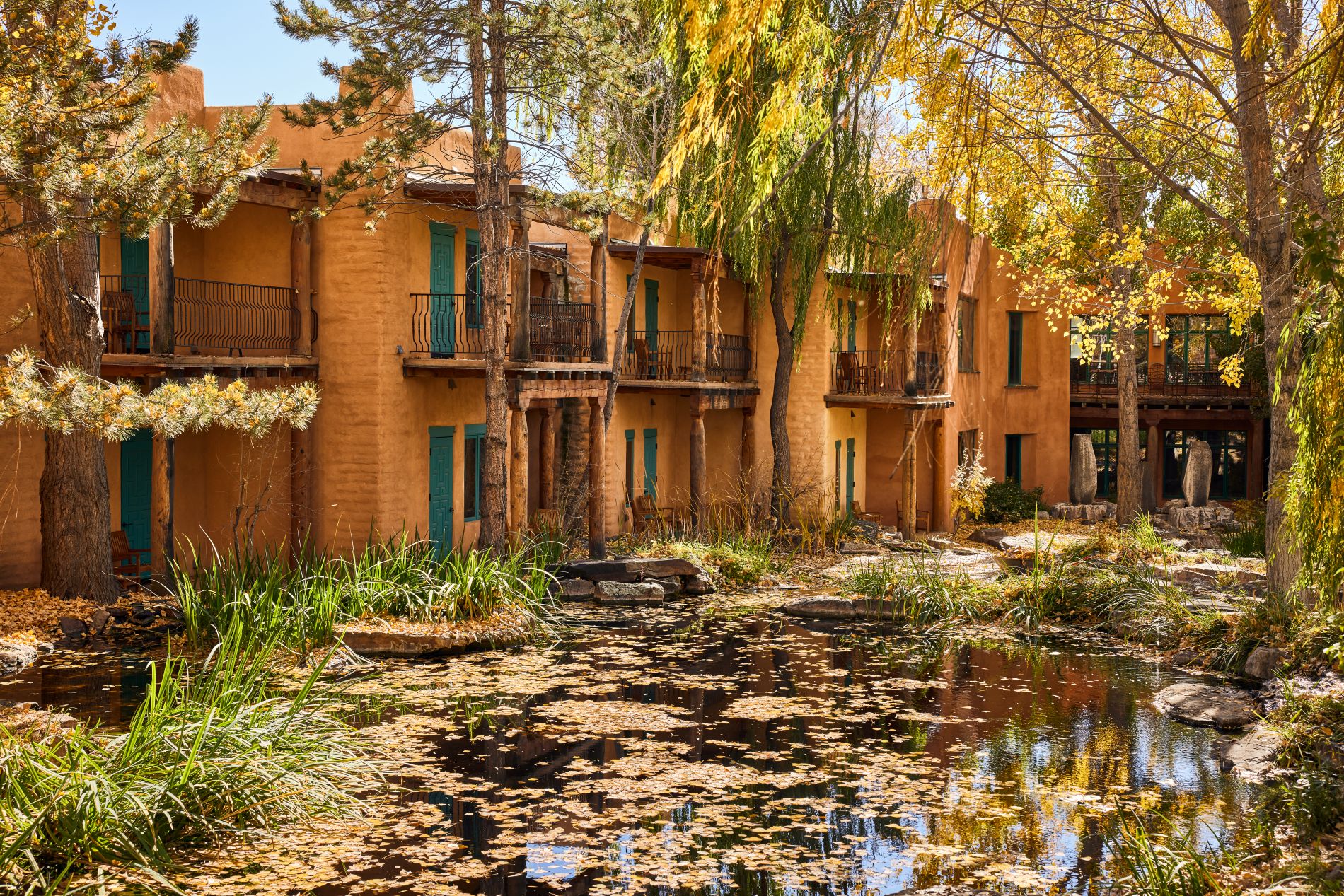 Grounds in Fall with trees and adobe 2 story building with guest rooms