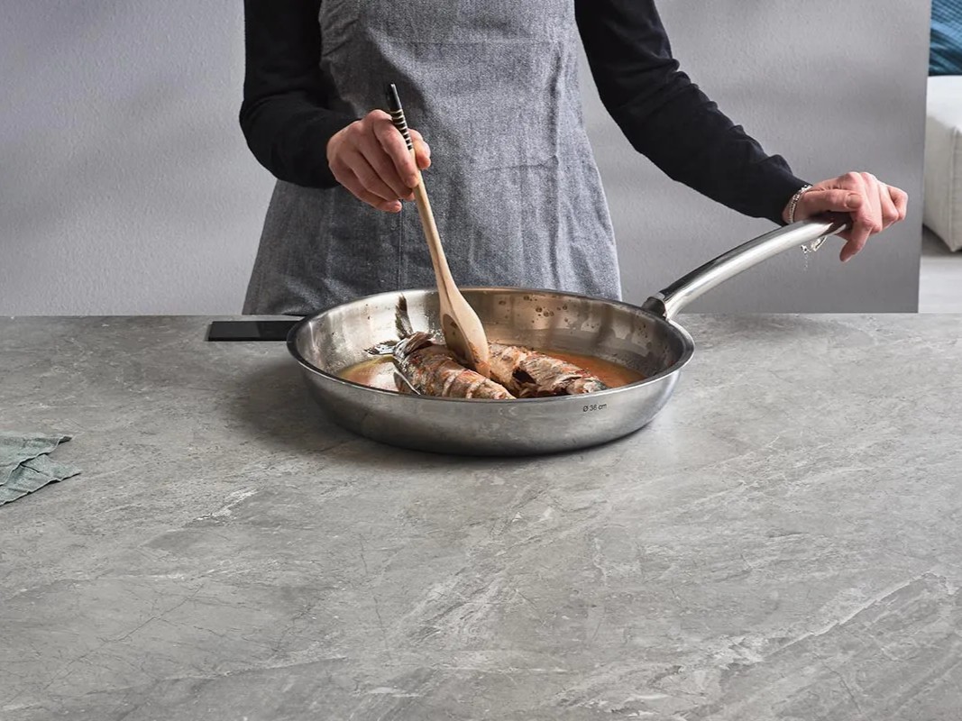 Pan of food cooking right on a stone countertop with an InvisaCook invisible cooktop hidden beneath