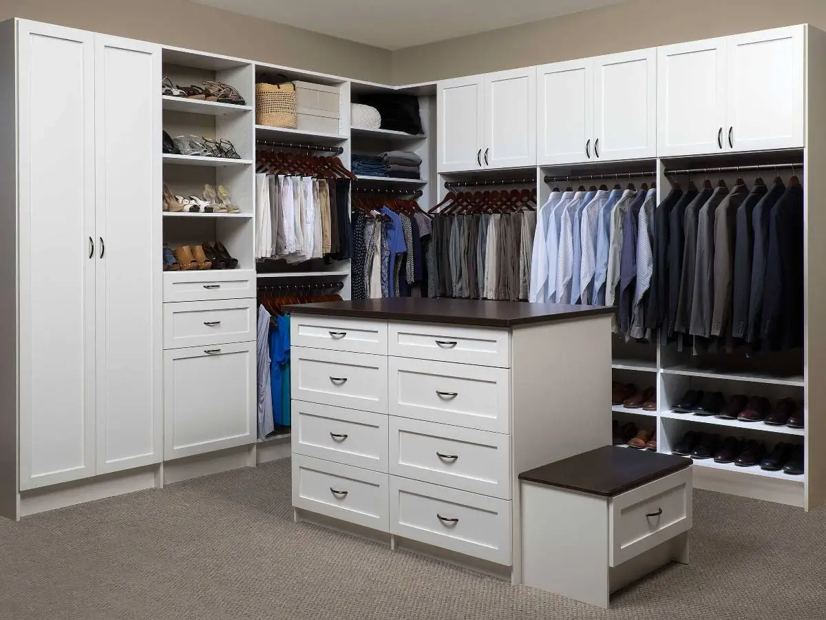 White shaker walk-in closet with an island and bench, tall cabinets, shoe shelves and sorted hanging