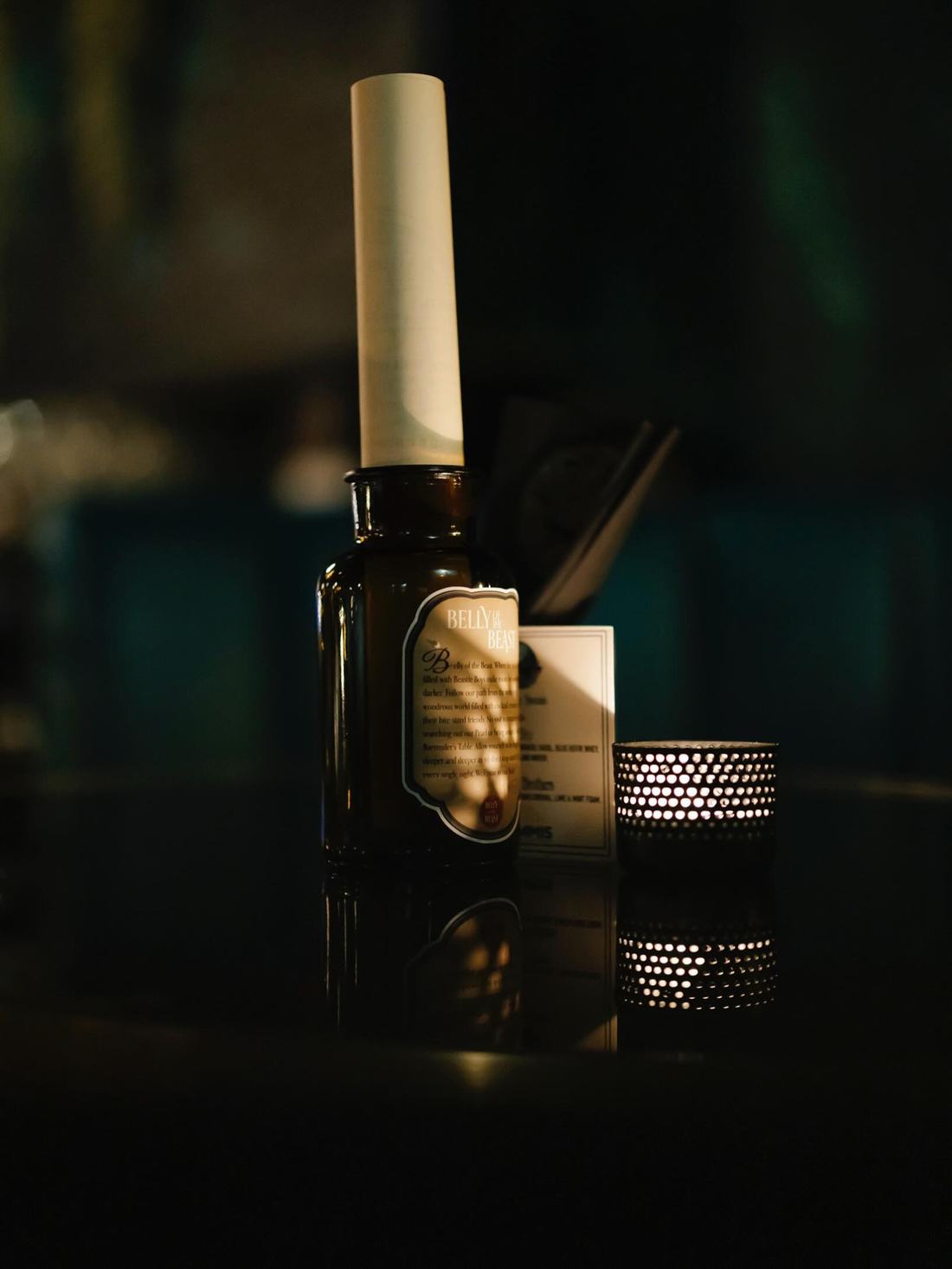 A cocktail menu rolled up as a message in a bottle