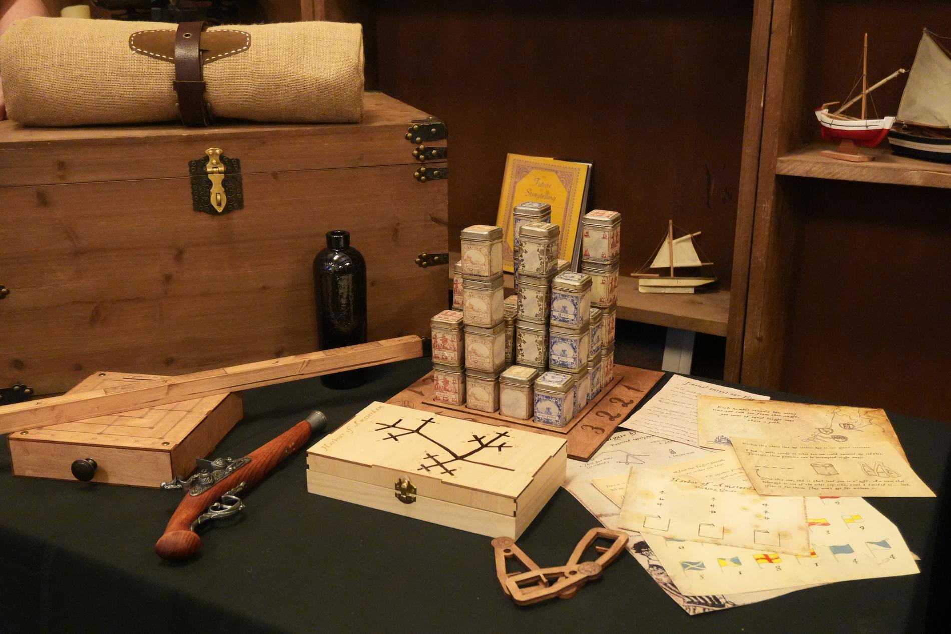 A Parlay table: an open sea trunk, spice tins, charts and a small ship