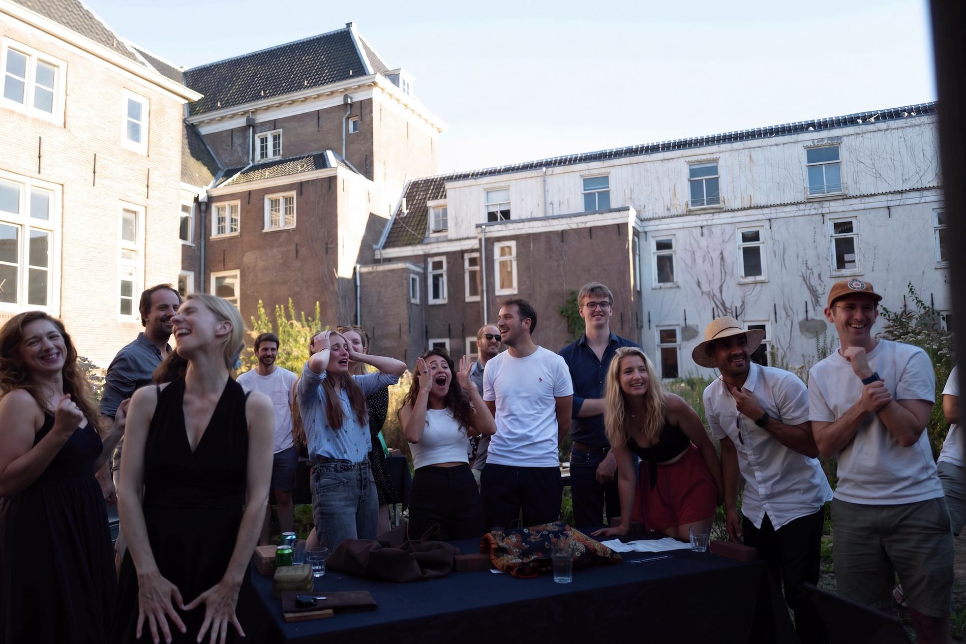 A team laughing and cheering around a table in an Amsterdam garden