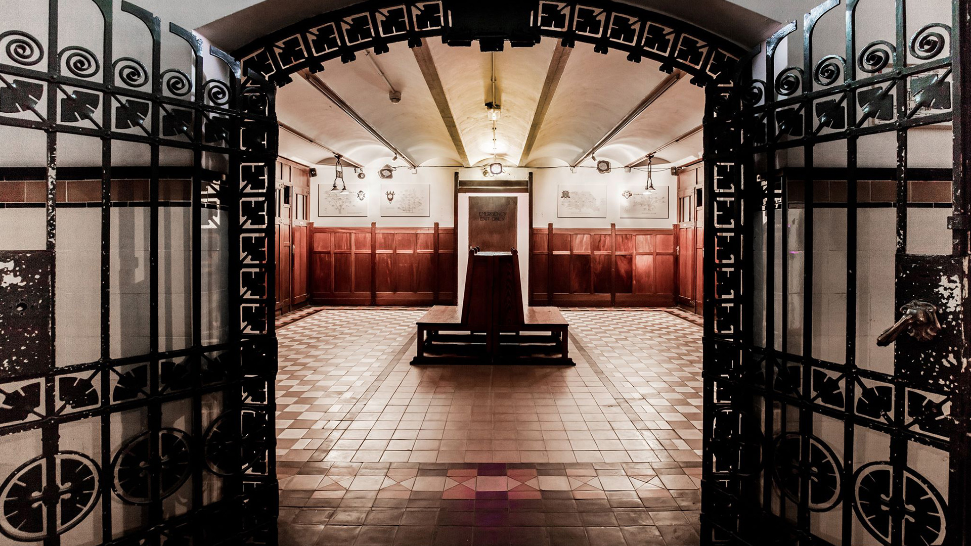 The Vault's open metallic gate, leading into a well-lit room, with two benches in the middle of it