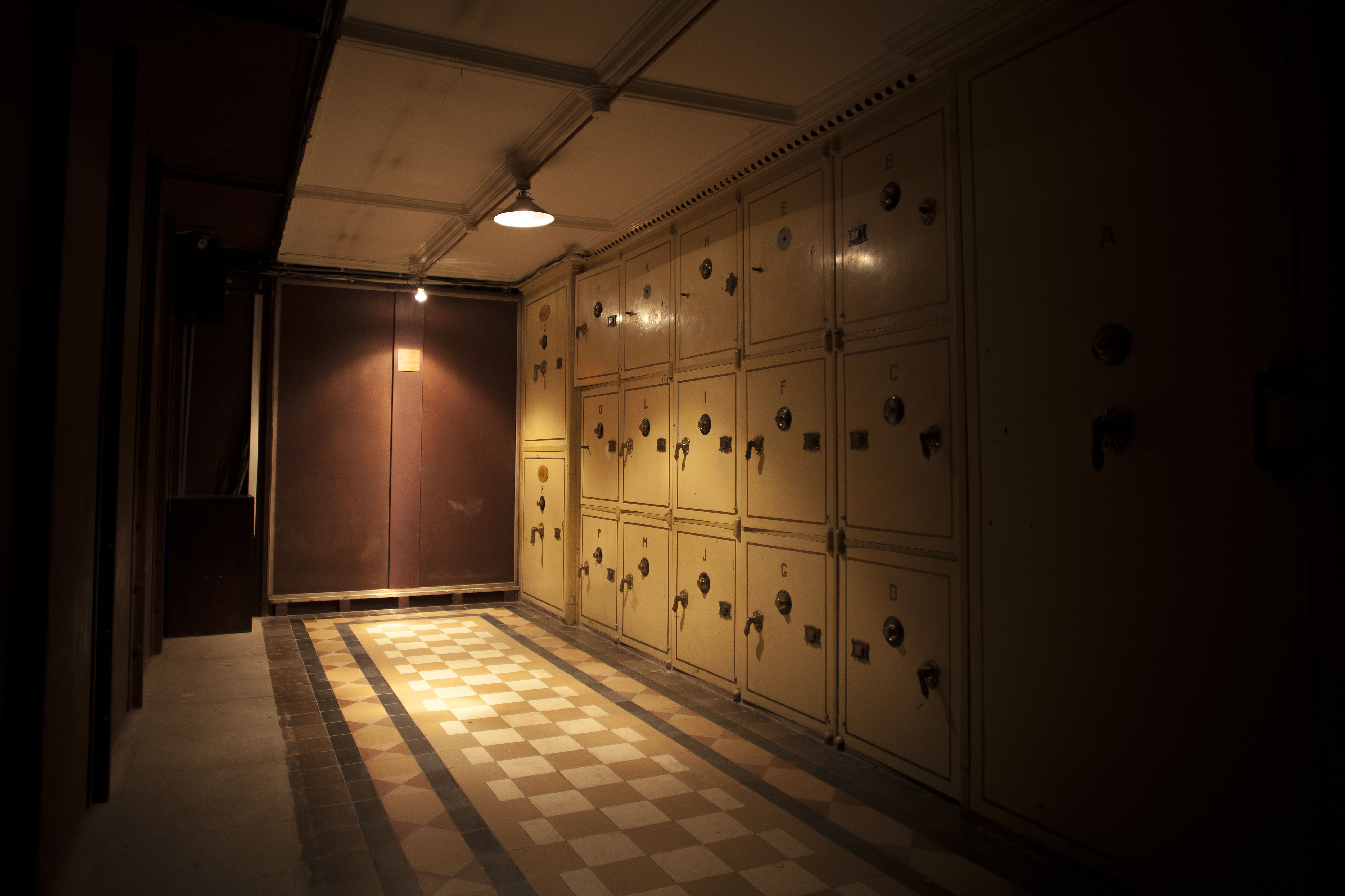 dim light hallway, with closed metallic safes forming one of the walls in the vault escape room in amsterdam