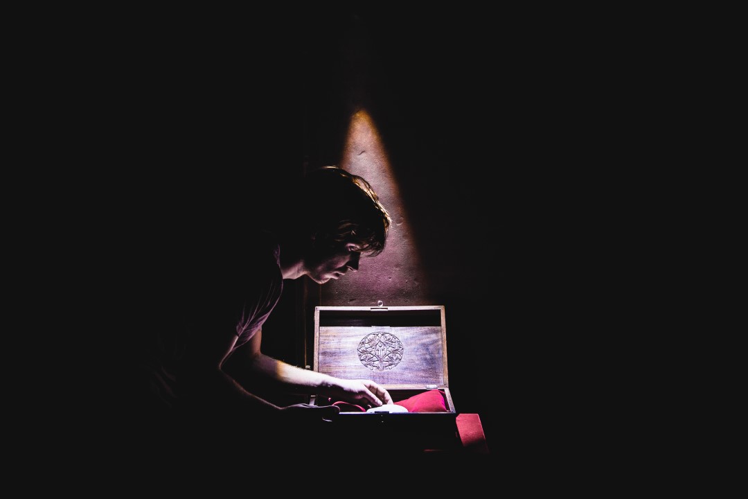 a dark room in the vault escape room in amsterdamwith one light projected onto a box and a man who takes a jewel out of the box