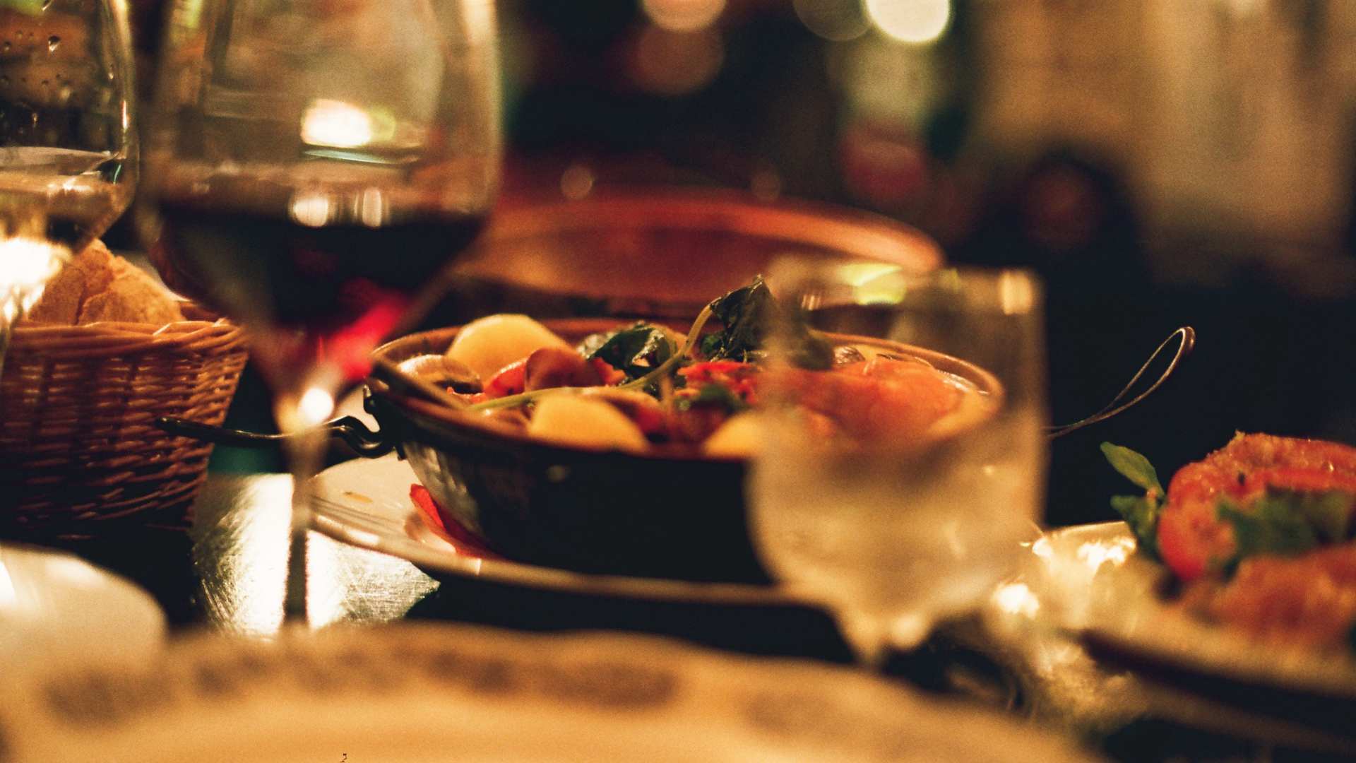 Atmospheric close-up of a gourmet Mediterranean meal and wine glasses at a cozy restaurant in Amsterdam.