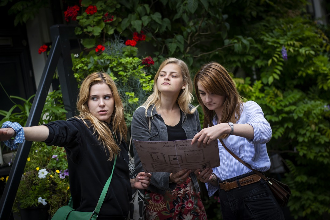 Three players navigating the streets of Amsterdam using a map to solve the Atlantis Protocol city game by Sherlocked.