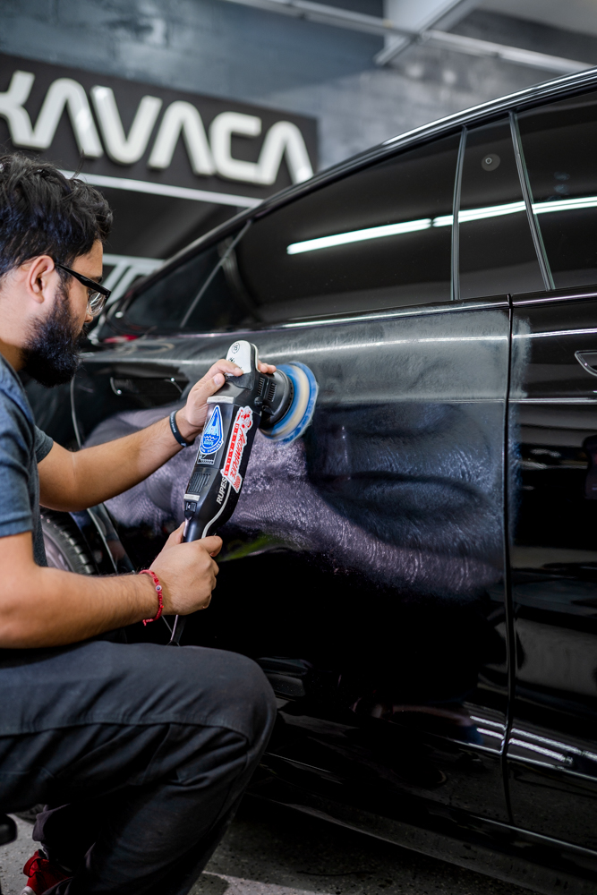 Paint correction on the side of a black Tesla Model S before coating