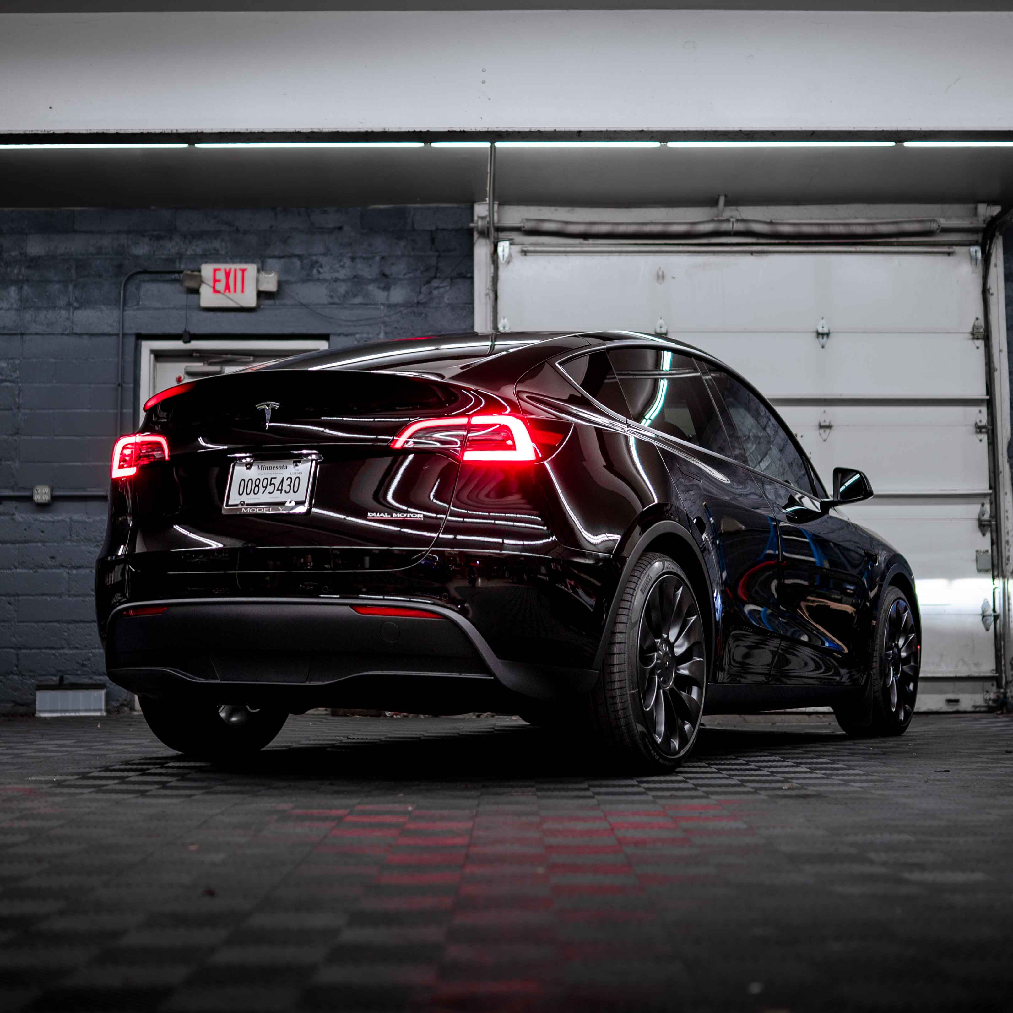 Rear three-quarter view of a black Tesla Model Y with its taillights lit