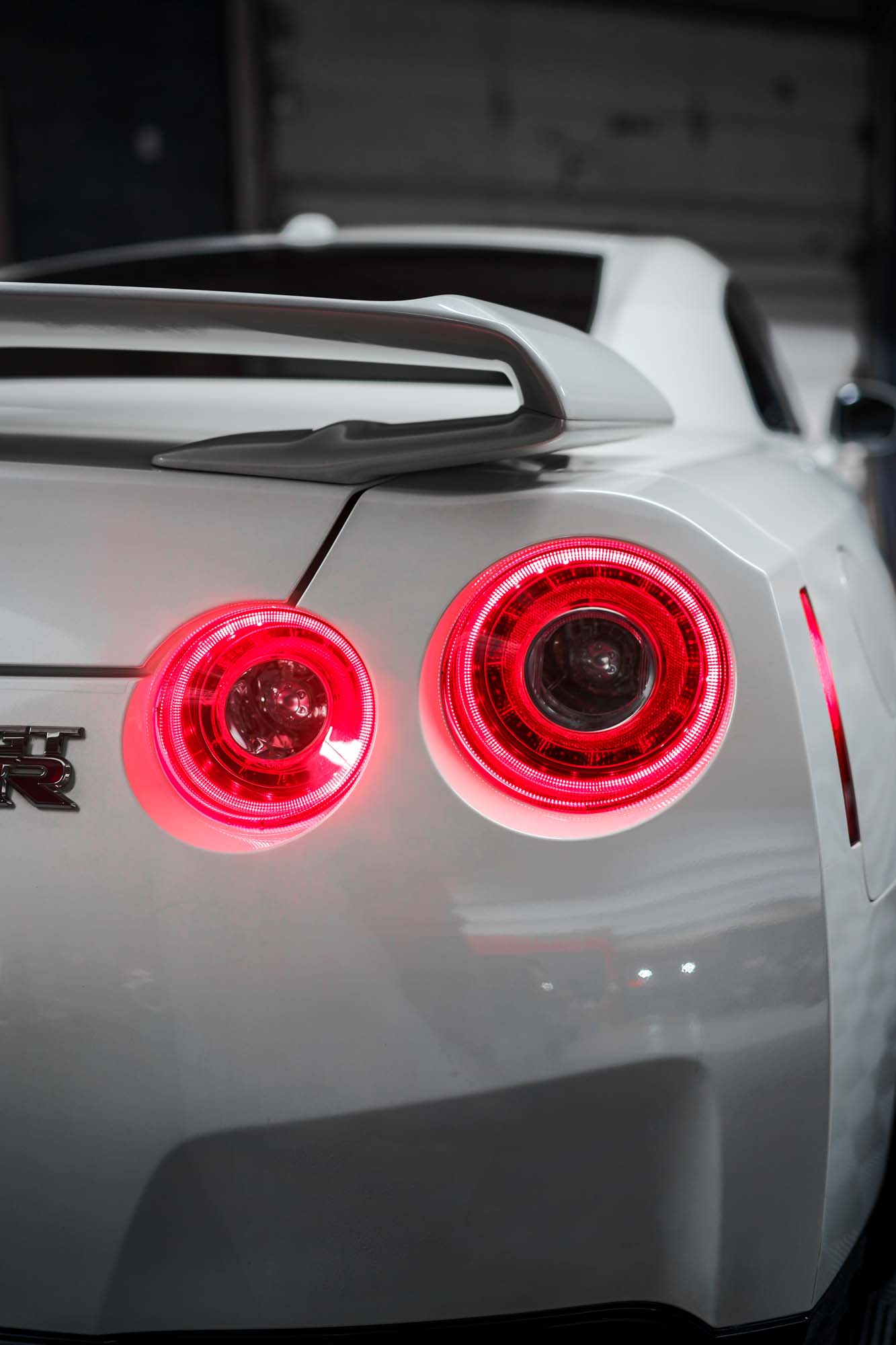 Round taillights glowing on the white Nissan GT-R