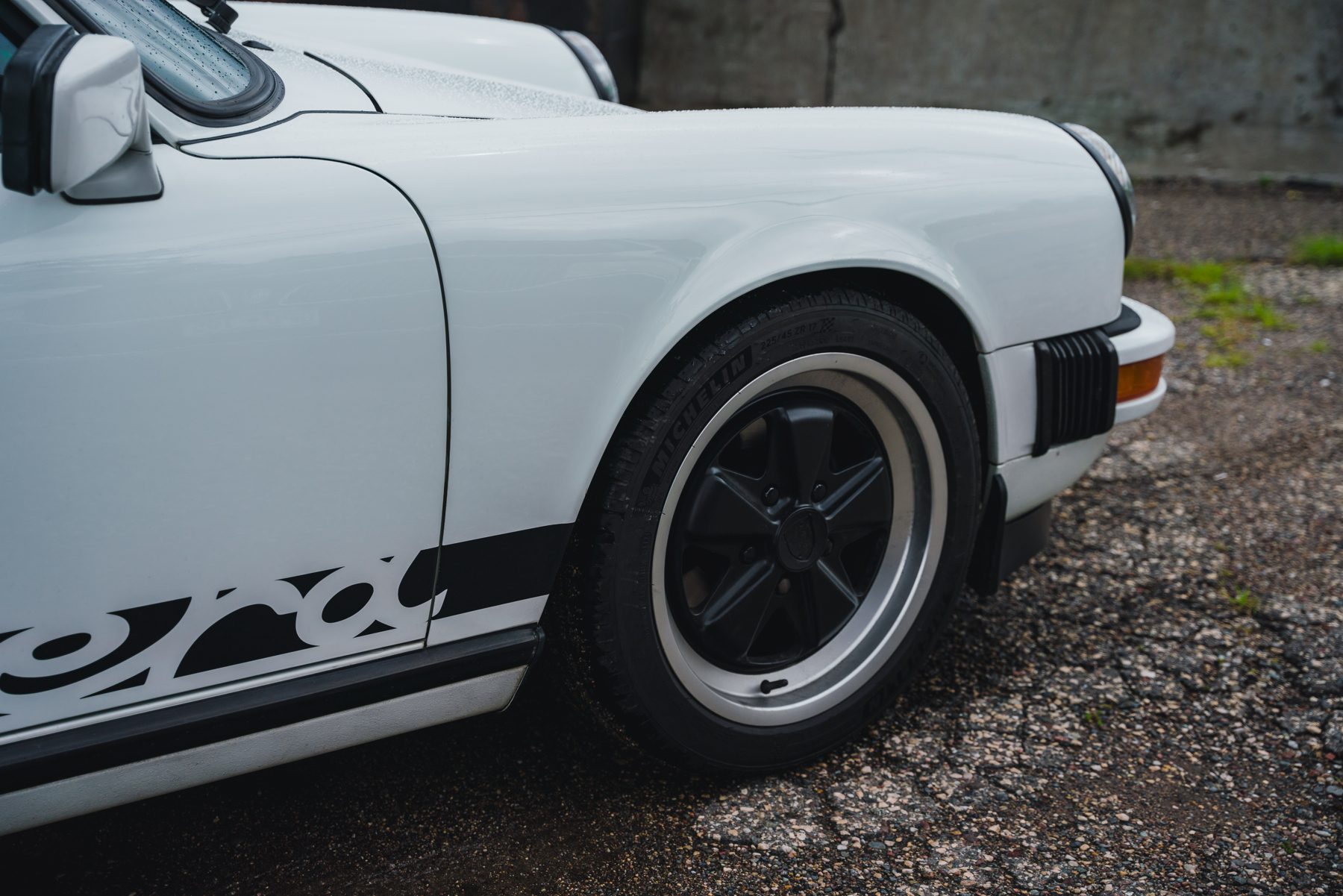 Side view of a white classic Porsche 911 with black Carrera script