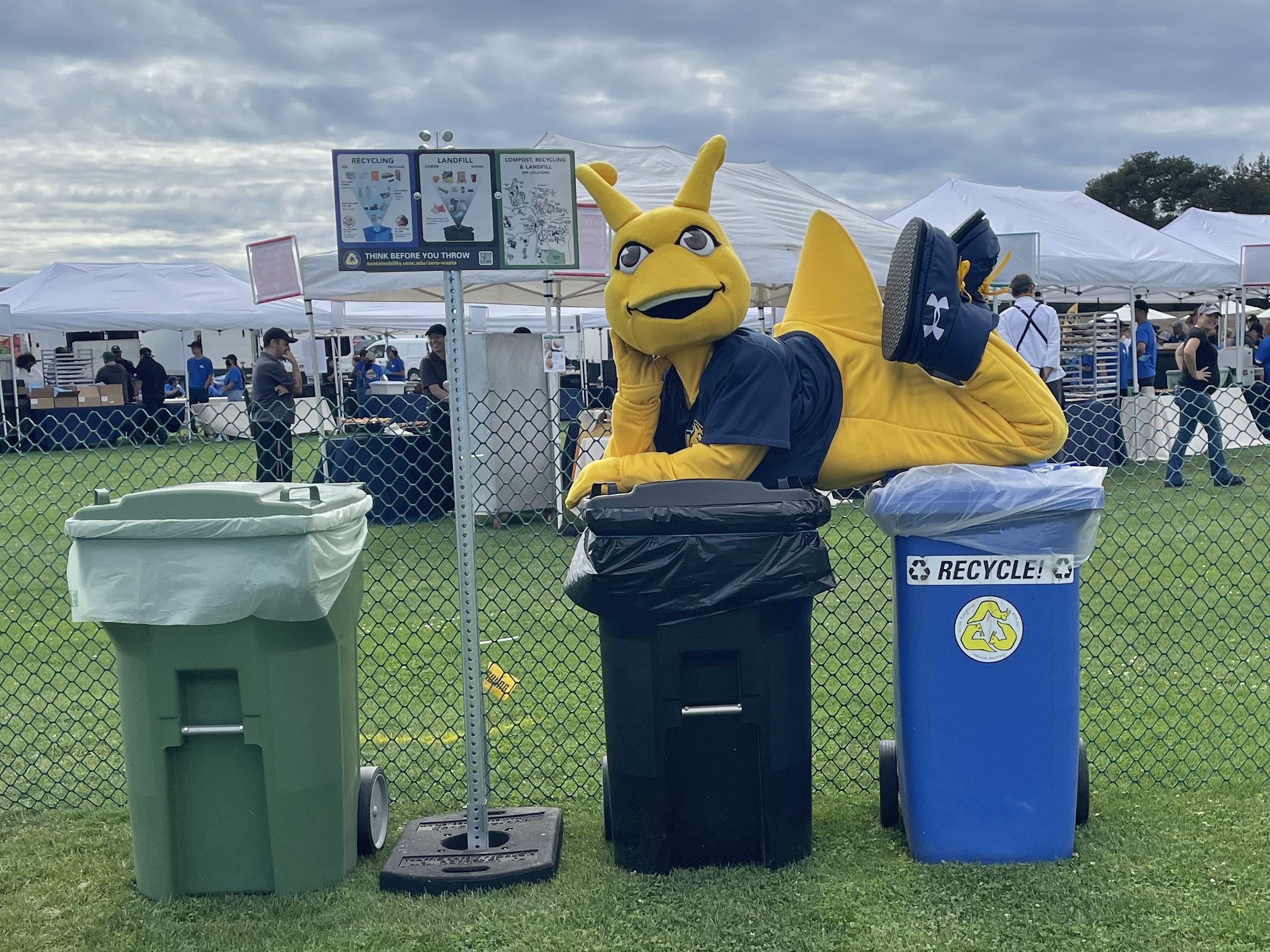 A group of students and staff under an outdoor tent labeled Office of Sustainability.