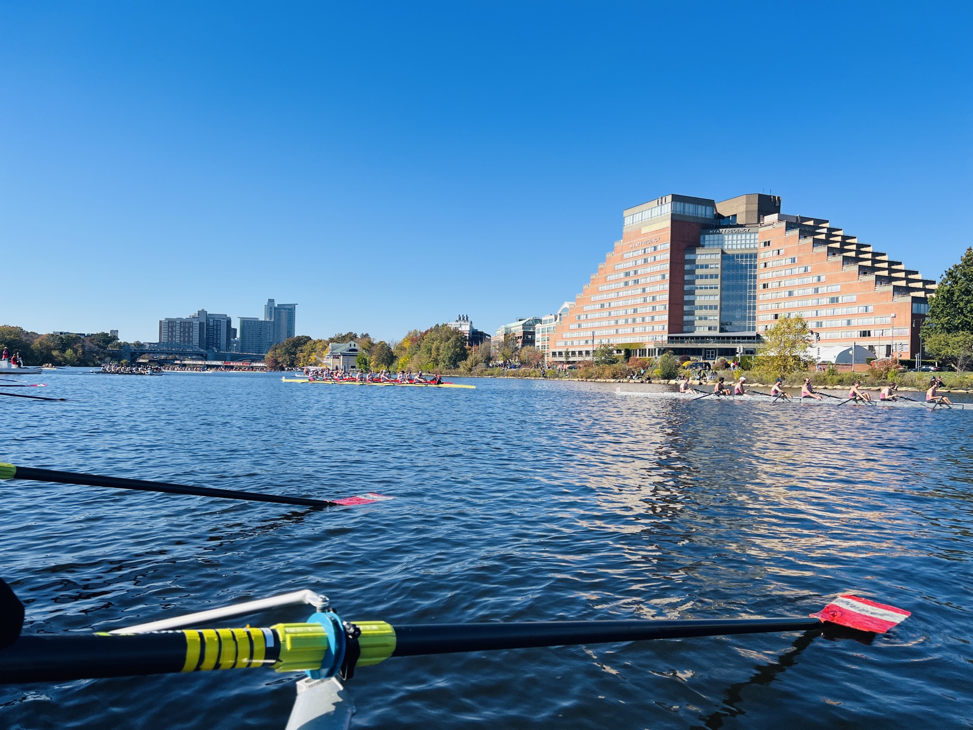 View from a rowing shell waiting near the start of the Head of the Charles, with other crews and the Hyatt Regency Cambridge