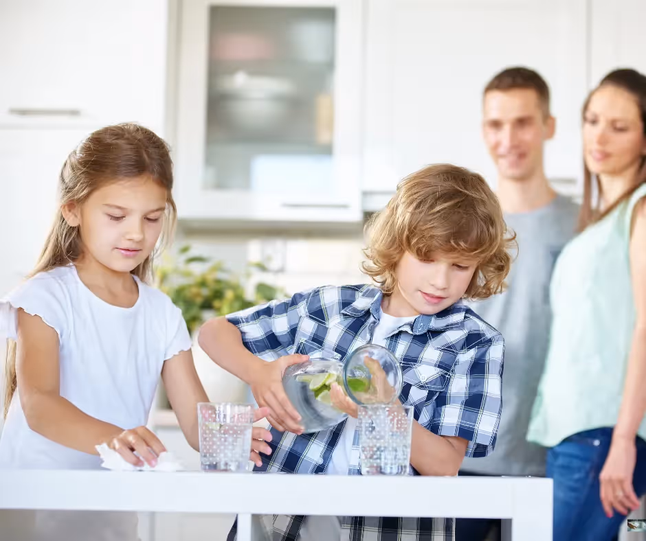 Kids pouring water into cup with parents happy in the background