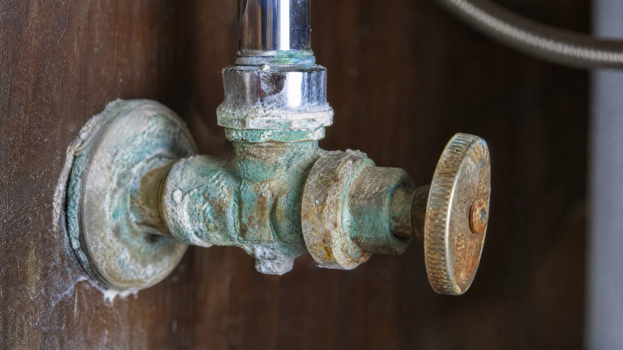 Close up of a heavily corroded under-sink water shut-off valve covered in mineral deposits.