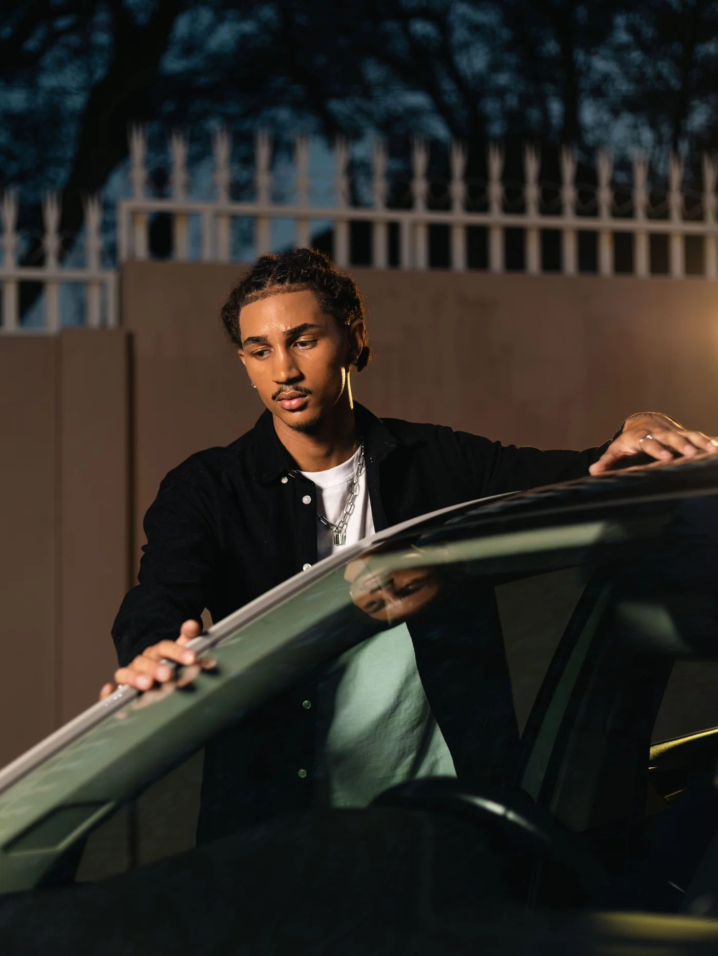 Young man standing at his car door at night