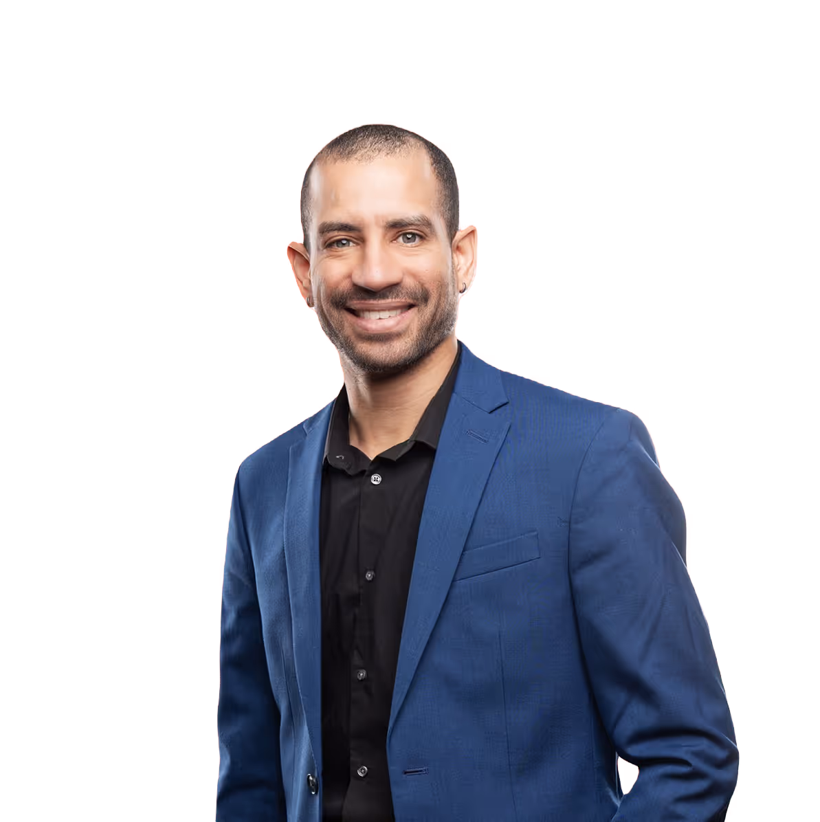 A smiling man with short hair and a thick beard is wearing a blue blazer over a black shirt, set against a red background.