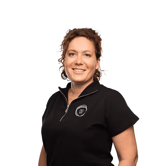 A smiling woman with curly hair wearing a black zip-up top with a tooth-shaped logo on the chest.